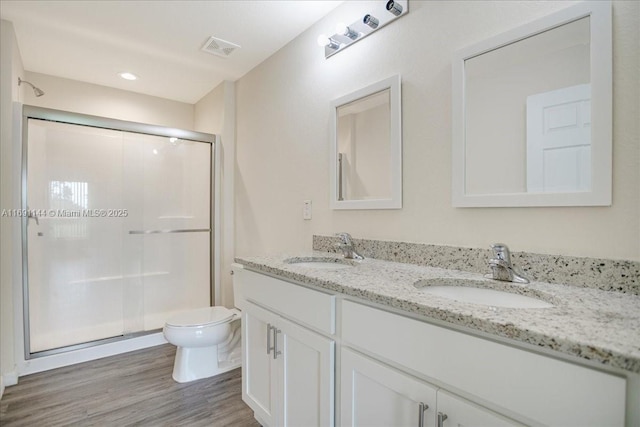 bathroom featuring hardwood / wood-style floors, vanity, toilet, and a shower with shower door