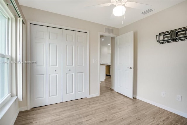 unfurnished bedroom with multiple windows, ceiling fan, a closet, and light hardwood / wood-style flooring