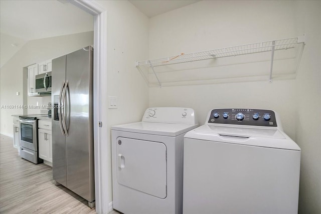 washroom with washer and dryer and light hardwood / wood-style flooring