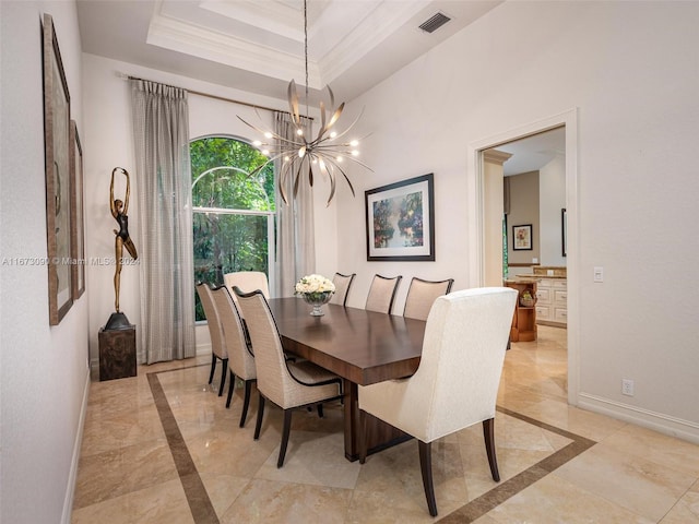 dining area with a chandelier, a tray ceiling, and ornamental molding