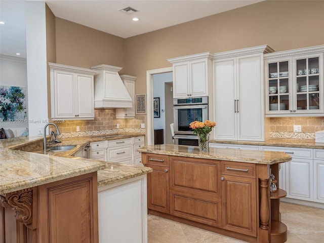 kitchen featuring light stone countertops, sink, double oven, and white cabinets