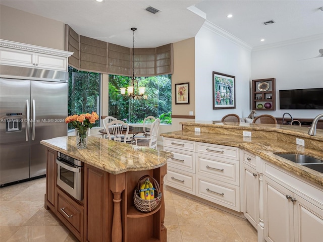 kitchen with crown molding, stainless steel appliances, decorative light fixtures, light stone countertops, and sink