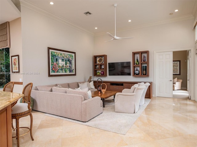 living room with a high ceiling, ceiling fan, and crown molding