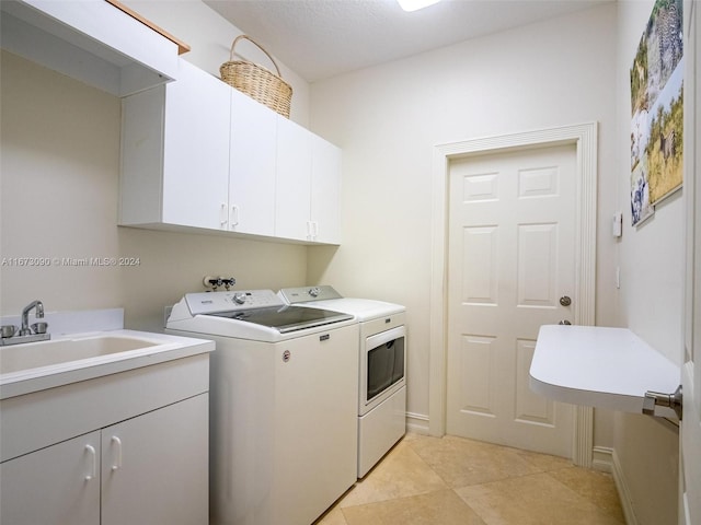 laundry area with a textured ceiling, light tile patterned floors, cabinets, sink, and washer and dryer