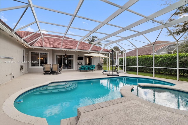 view of pool with a patio area, a pool with connected hot tub, and glass enclosure