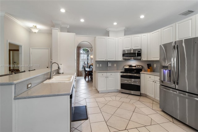 kitchen with stainless steel appliances, a sink, crown molding, white cabinets, and light tile patterned flooring