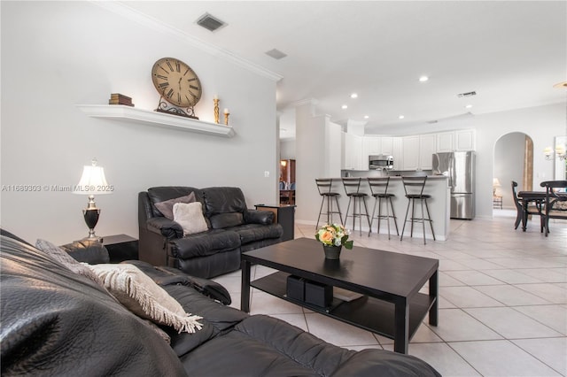 living room with arched walkways, ornamental molding, light tile patterned flooring, recessed lighting, and baseboards