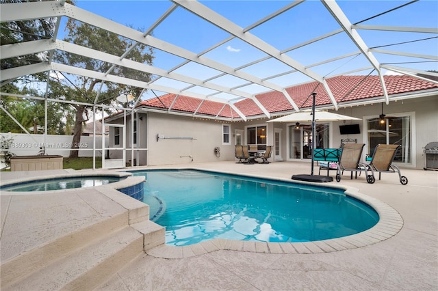 view of pool featuring a ceiling fan, a patio, outdoor dining area, a pool with connected hot tub, and a lanai