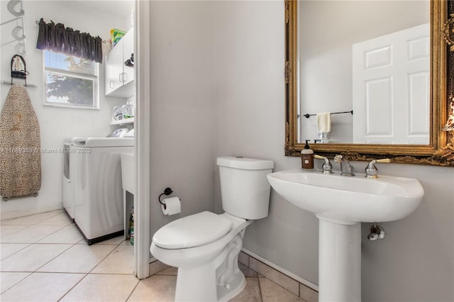 half bathroom with washer / dryer, tile patterned flooring, toilet, and baseboards