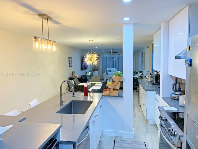 kitchen featuring appliances with stainless steel finishes, white cabinetry, hanging light fixtures, and sink