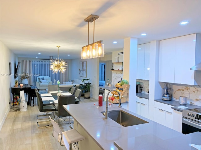 kitchen with light hardwood / wood-style floors, sink, white cabinetry, and hanging light fixtures