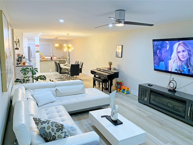 living room featuring wood-type flooring and ceiling fan with notable chandelier