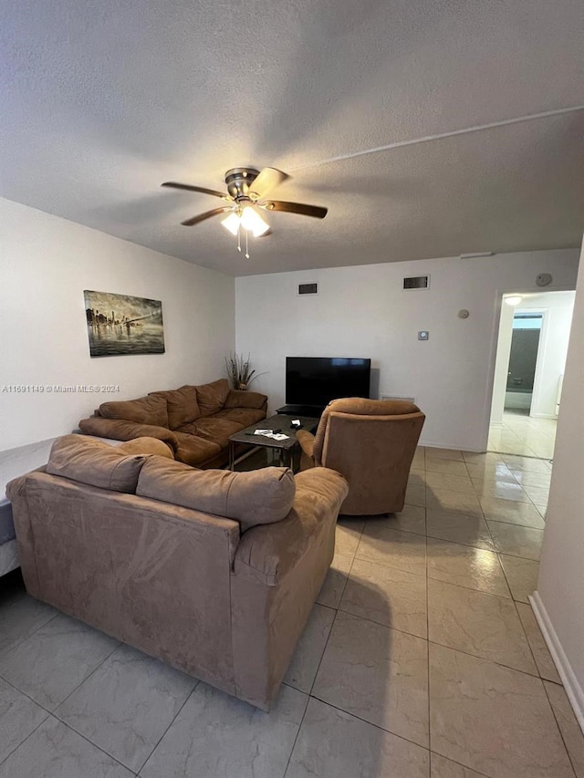 living room with ceiling fan and a textured ceiling