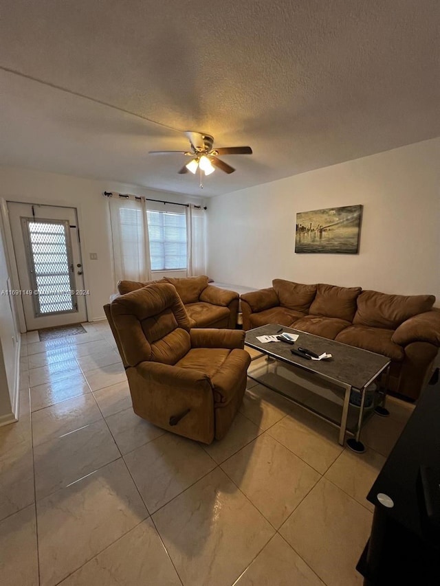 living room with ceiling fan, a textured ceiling, and light tile patterned floors