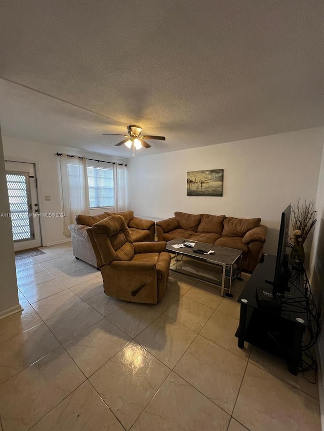 living room with light tile patterned flooring, ceiling fan, and a textured ceiling