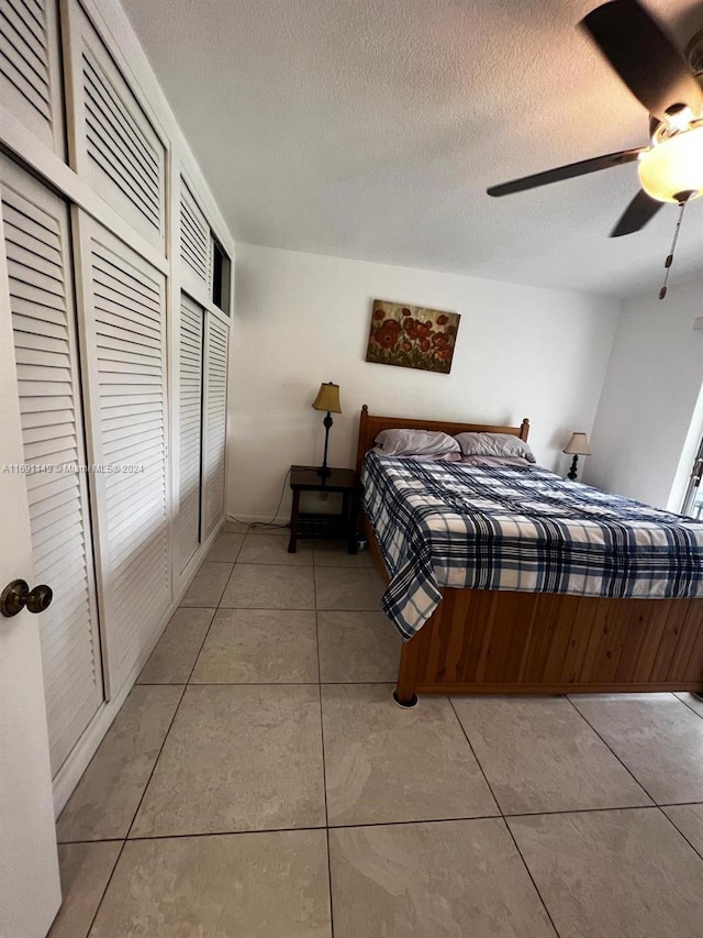 tiled bedroom with ceiling fan and a textured ceiling