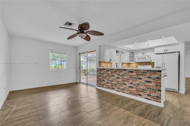 kitchen with white cabinets, white appliances, and hardwood / wood-style floors