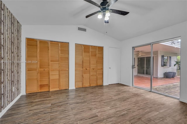 unfurnished bedroom with multiple closets, wood-type flooring, ceiling fan, and vaulted ceiling