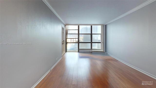 empty room with crown molding, hardwood / wood-style floors, and expansive windows