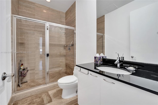 bathroom with tile patterned flooring, vanity, toilet, and a shower with shower door