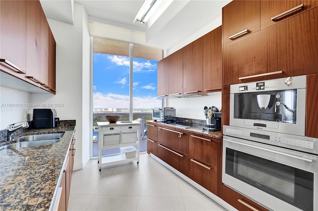 kitchen featuring oven, sink, and dark stone counters