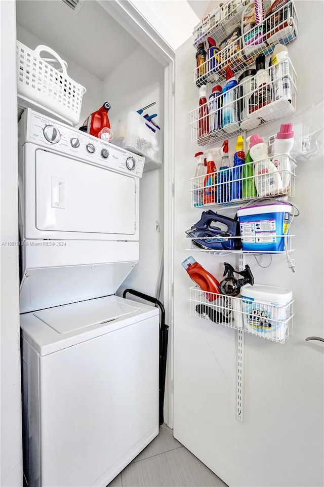 laundry area with light tile patterned floors and stacked washer / drying machine