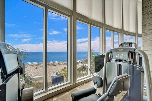 sunroom featuring a beach view and a water view