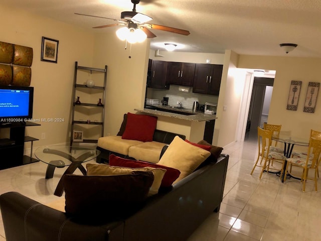 living room with ceiling fan, a textured ceiling, and light tile patterned floors