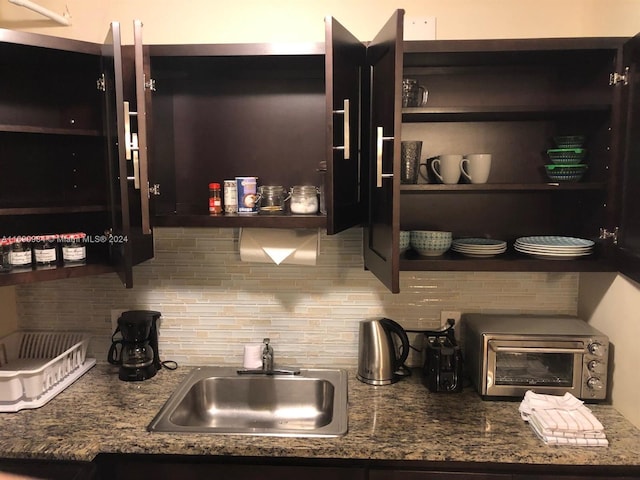 kitchen with dark stone counters, sink, and backsplash