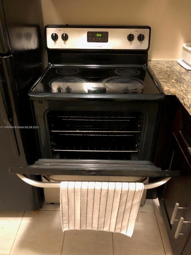 room details featuring electric range oven, light stone counters, and light tile patterned flooring