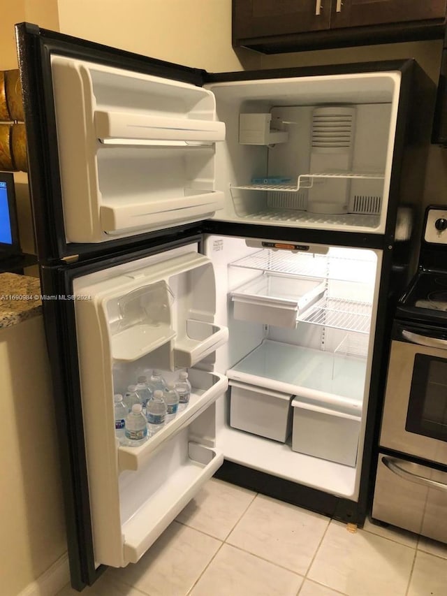 kitchen with light tile patterned floors, white fridge, and stainless steel range with electric stovetop