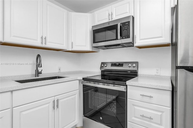 kitchen with stainless steel appliances, white cabinetry, and sink