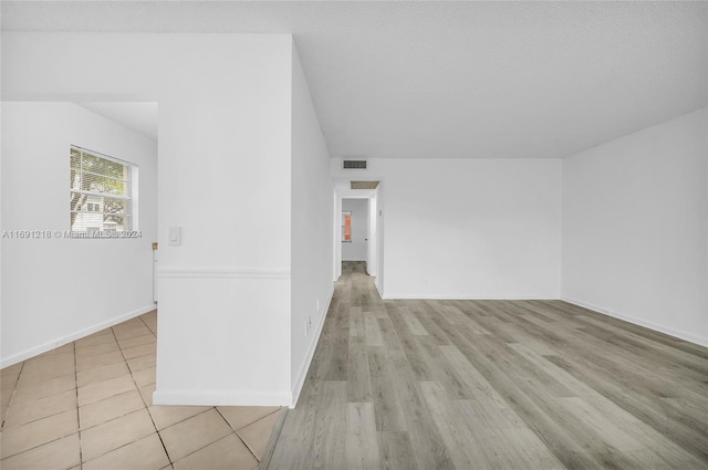 spare room with light wood-type flooring and a textured ceiling