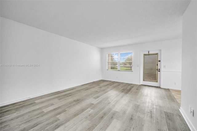 empty room with light hardwood / wood-style floors and a textured ceiling