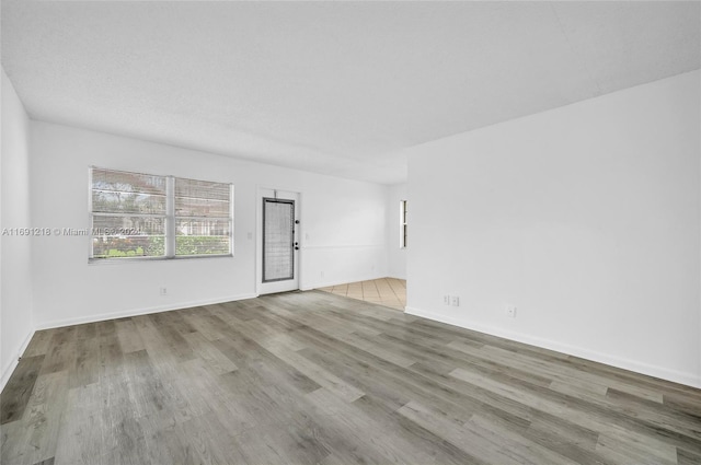 empty room with light hardwood / wood-style floors and a textured ceiling