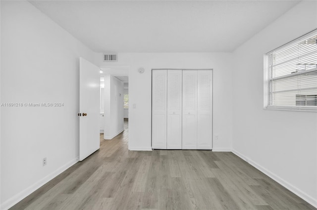 unfurnished bedroom with light wood-type flooring and a closet