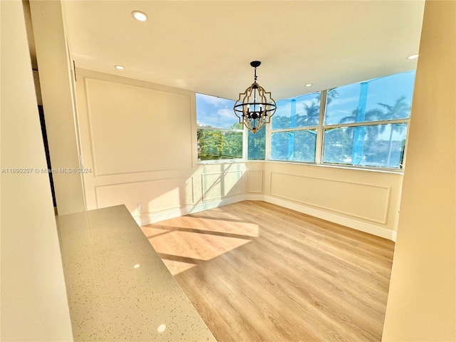 unfurnished dining area featuring hardwood / wood-style floors and a chandelier