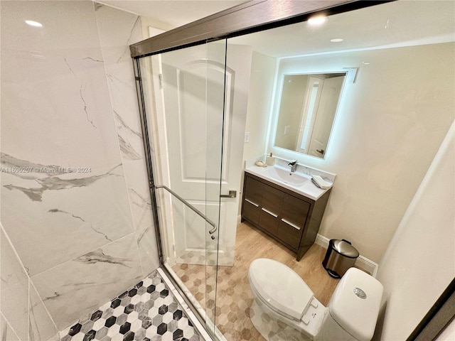 bathroom featuring toilet, vanity, wood-type flooring, and a shower with door