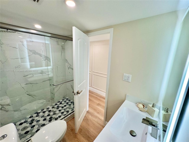 bathroom with toilet, sink, hardwood / wood-style floors, and a shower with door