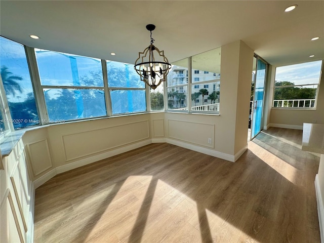16546 NE 26th Ave Unit 3G, North Miami Beach, FL 33160 - unfurnished dining area featuring wood finished floors, a chandelier, a decorative wall, and recessed lighting
