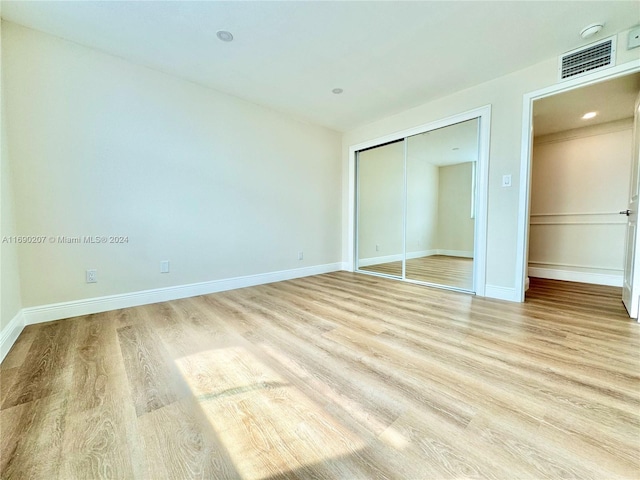 unfurnished bedroom with light hardwood / wood-style flooring and a closet