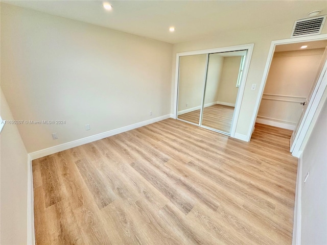 unfurnished bedroom with light hardwood / wood-style flooring and a closet