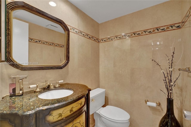 bathroom with tile walls, vanity, and toilet