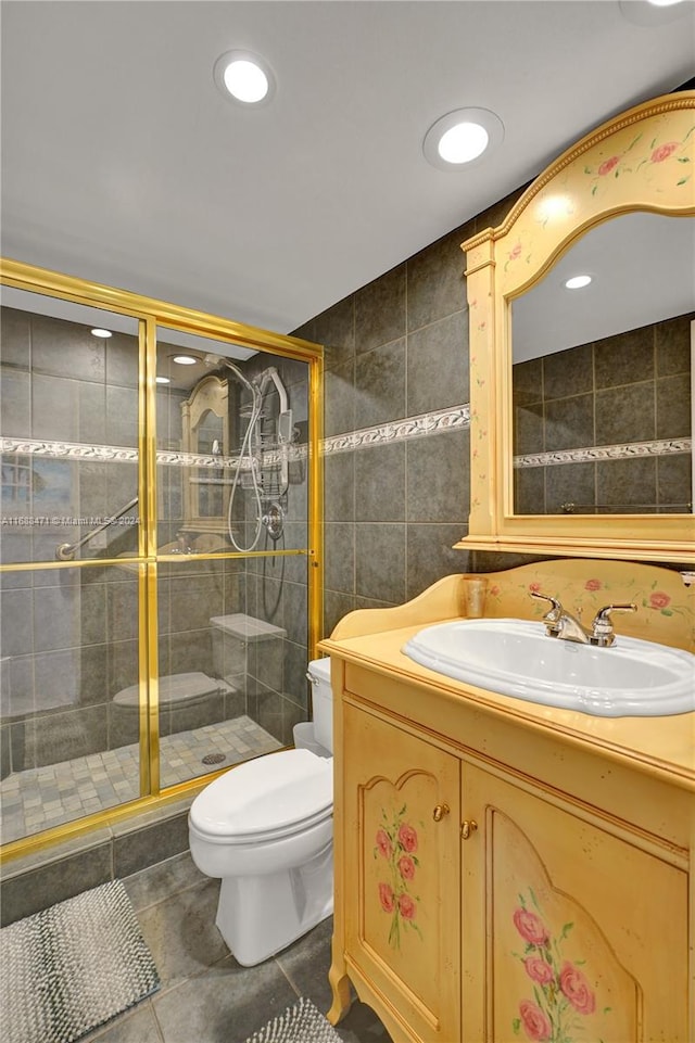 bathroom featuring toilet, tile walls, tile patterned flooring, vanity, and a shower with shower door