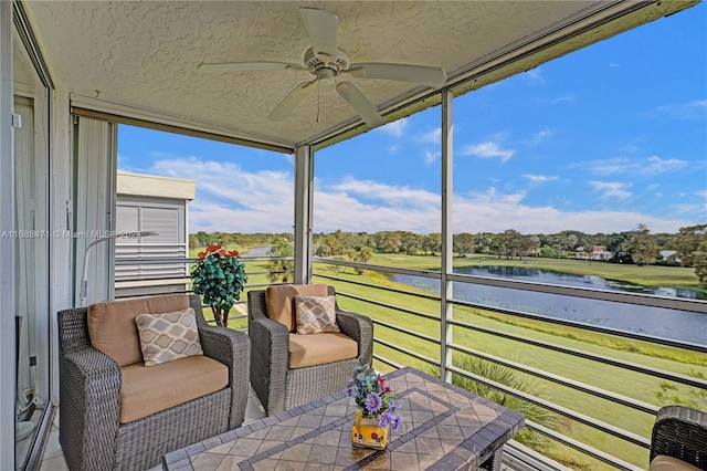 sunroom featuring ceiling fan and a water view