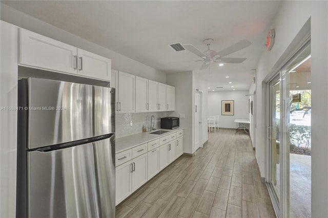 kitchen with white cabinetry, sink, stainless steel fridge, and light wood-type flooring