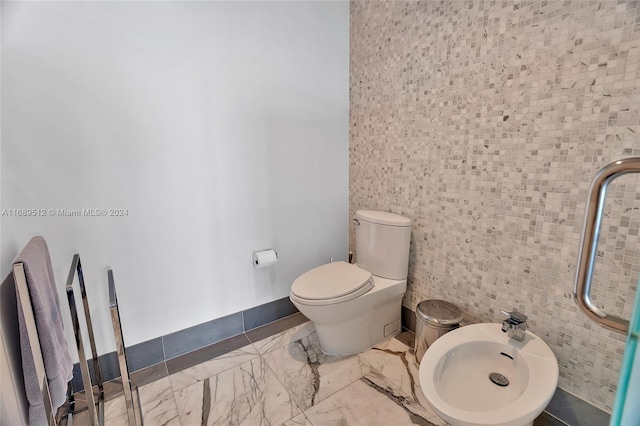 bathroom with toilet, tile walls, and a bidet