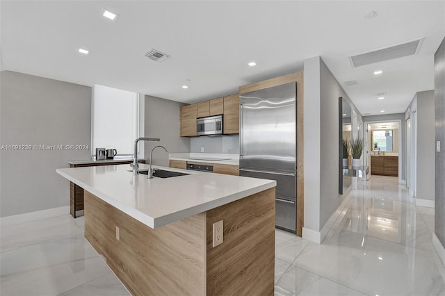 kitchen featuring sink, a center island with sink, and stainless steel appliances