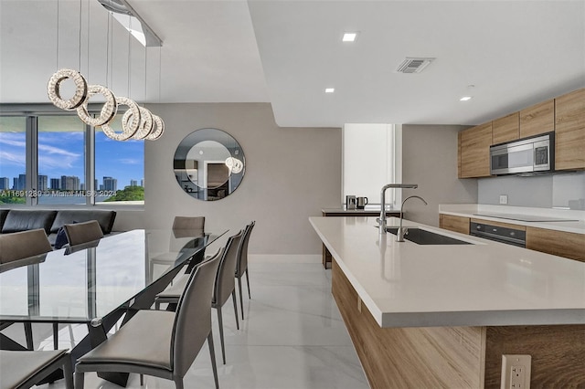 16385 NE Biscayne Blvd Unit 307 2Parking, North Miami Beach, FL 33160 - kitchen featuring stainless steel microwave, a sink, modern cabinets, a center island with sink, and brown cabinetry
