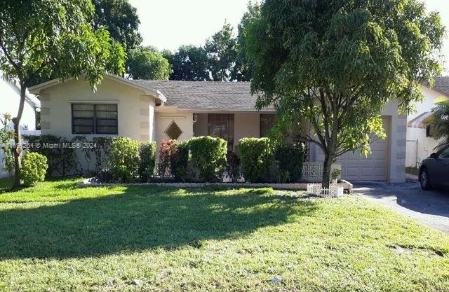 ranch-style house featuring a garage and a front lawn